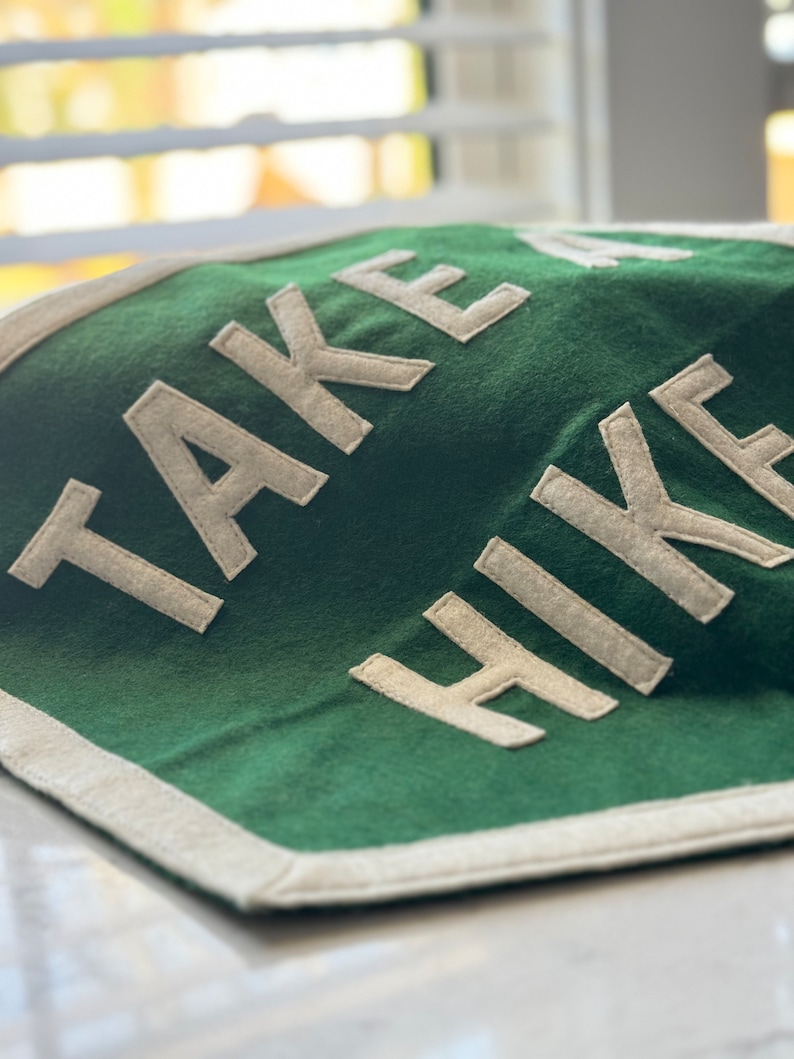 May include: A green felt pennant with white felt lettering that reads "TAKE A HIKE".