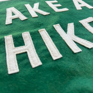 May include: A green fabric banner with white felt lettering that reads "TAKE A HIKE".