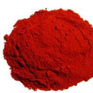 May include: A pile of bright red paprika powder, a common spice used in cooking.