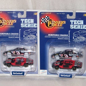 May include: Two NASCAR Winner's Circle Tech Series diecast cars, 1/64 scale, featuring a removable chassis. The cars are black and red, with the number 3 and Goodwrench branding. Packaging includes the text "Dale Earnhardt".