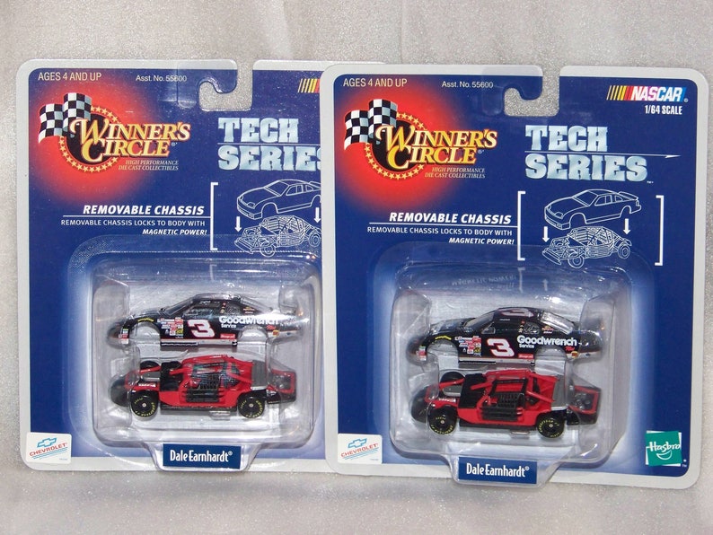 May include: Two NASCAR Winner's Circle Tech Series diecast cars, 1/64 scale, featuring a removable chassis. The cars are black and red, with the number 3 and Goodwrench branding. Packaging includes the text "Dale Earnhardt".