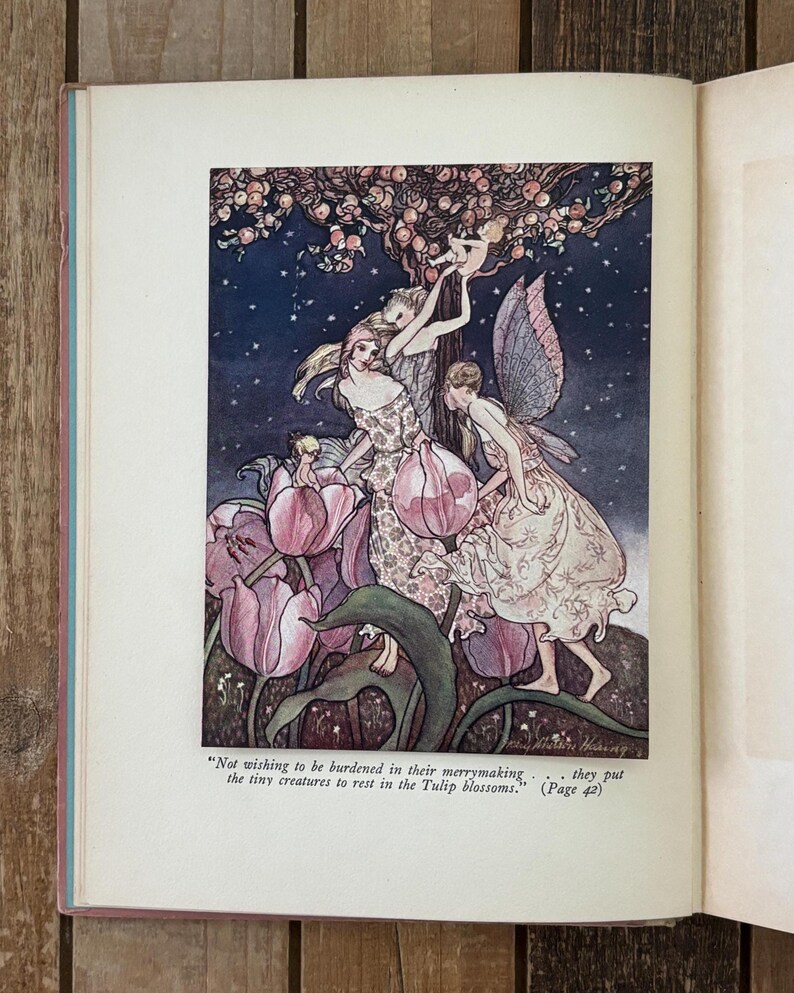 May include: An open book page featuring a color illustration of winged figures among pink tulip blossoms under a starry sky. The text below the image reads: Not wishing to be burdened in their merrymaking . . . they put the tiny creatures to rest in the Tulip blossoms. (Page 42)