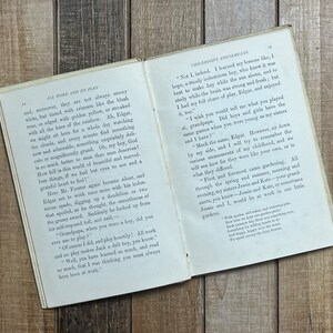May include: An open book with yellowed pages and a brown leather cover. The book is titled "All Work and No Play" and features text about the importance of play and the beauty of nature. The book is open to a page with the text "Not I, indeed. I learned my lessons like, I hope, a steady industrious boy, who knew it was best to make hay while the sun shone, and to study while the brain was strong and fresh; but I had my full share of play, Edgar, and enjoyed it, too."