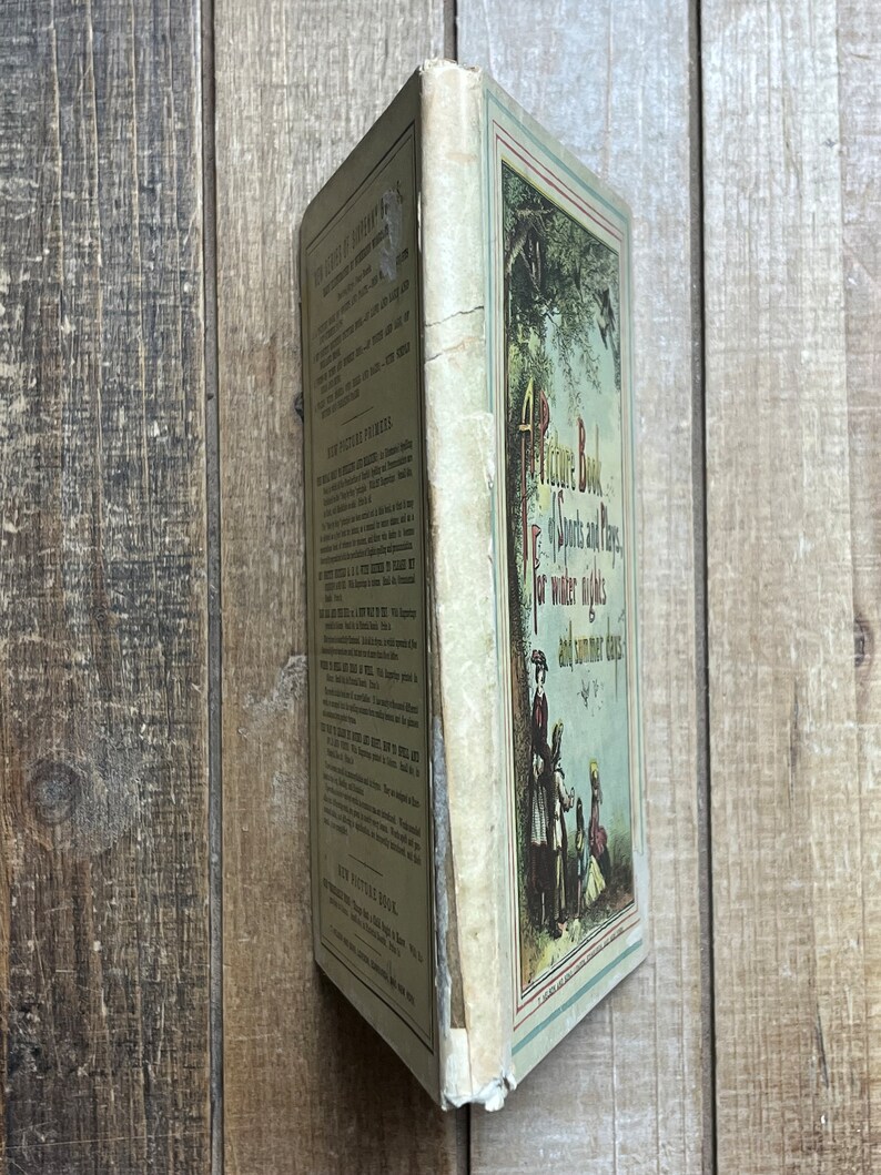 May include: A vintage children's book titled "A Picture Book of Sports and Plays for Winter Nights and Summer Days". The cover features a colorful illustration of children playing in a snowy forest.