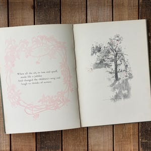 May include: An open book with two pages. The left page features a light pink floral border surrounding the text: When all the air, to toss and quaff, made life a jubilee And changed the children's song and laugh to shrieks of ecstasy. The right page shows a grey ink illustration of a tree.