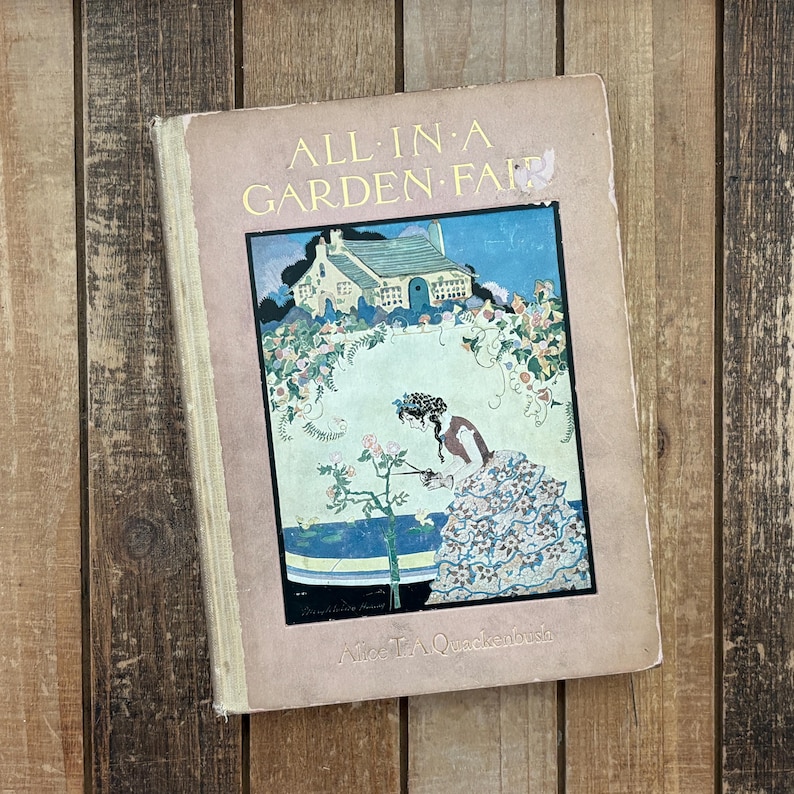 May include: A hardcover book titled All in a Garden Fair by Alice T. A. Quackenbush. The cover is light brown with a central illustration featuring a cottage, a garden, and a figure tending to roses. The text is printed in gold lettering.