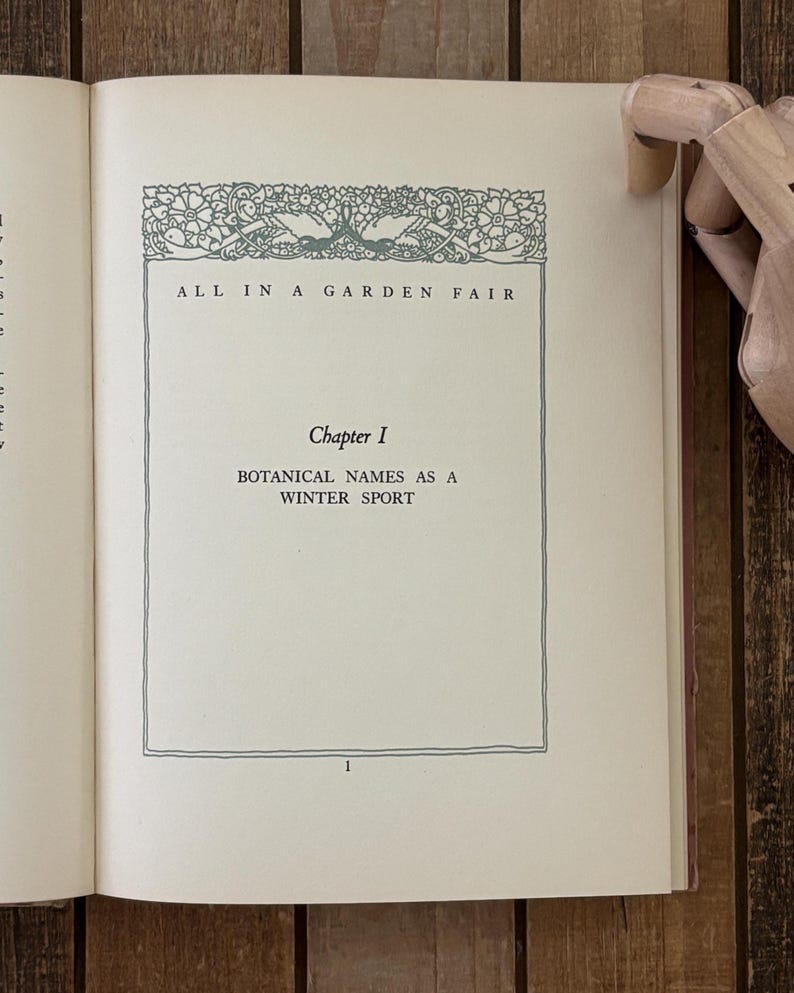 May include: An open book page featuring the title ALL IN A GARDEN FAIR, Chapter I, and the text BOTANICAL NAMES AS A WINTER SPORT. The page includes a decorative green floral border at the top and the number 1 at the bottom center of the page.