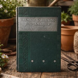 May include: A vintage book titled "Chemical Gardening for the Amateur" with a dark green cover and silver lettering. The book is surrounded by gardening tools and potted plants, suggesting a gardening theme. The book's cover has decorative floral elements.