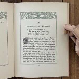 May include: An open book page titled III THE CLASSICS IN THE GARDEN with a decorative green border and a large drop cap letter T. The text discusses Apollo, Daphne, Pan, and Syrinx, with the page number 21 at the bottom center of the page.