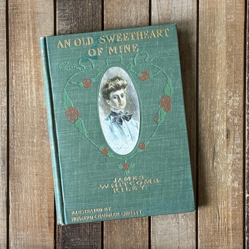 May include: A green hardcover book titled An Old Sweetheart of Mine by James Whitcomb Riley, illustrated by Howard Chandler Christy. The cover features a central oval portrait of a person with a bow tie, surrounded by a decorative floral vine design.