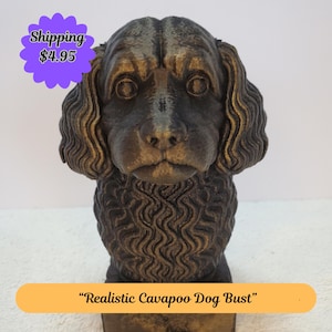 May include: A bronze-colored Cavapoo dog bust with detailed fur texture. The sculpture has a realistic appearance, with focused eyes and a slightly open mouth. The bust is labeled "Realistic Cavapoo Dog Bust".