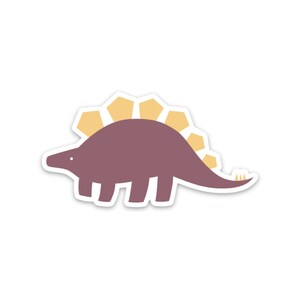 K&ouml;nnte beinhalten: Ein lila Dinosaurier mit einem gelben, stacheligen R&uuml;cken. Der Dinosaurier blickt nach links und hat ein einfaches, cartoonartiges Design.