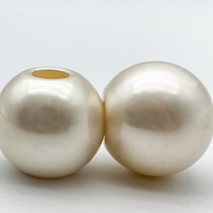 May include: Two large, white, round, smooth, plastic beads with a hole in the centre.