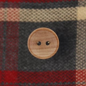 May include: A wooden button with two holes. The button is light brown and has a smooth surface.