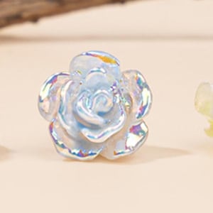 Könnte beinhalten: Eine irisierende blaue Glasrosenblütenperle. Die Perle hat ein 3D-Design und ist perfekt für die Schmuckherstellung.