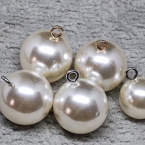 May include: Five white pearl buttons with silver and gold loop closures. The buttons are different sizes.