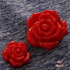 May include: Two red plastic rose-shaped buttons. The larger button is about 2 inches in diameter and the smaller button is about 1 inch in diameter.