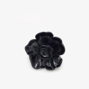 May include: A black flower-shaped ring with a glossy finish.