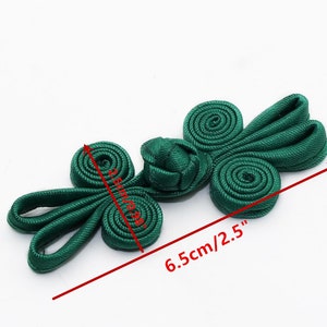May include: Green Chinese knot button with two loops on each side, measuring 2.5 inches long and 1 inch wide.