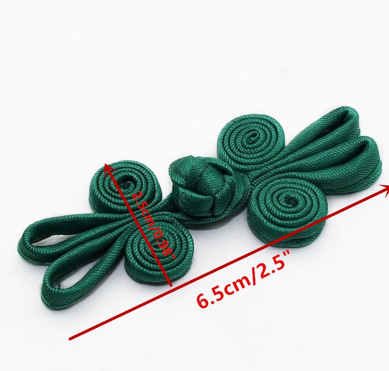 May include: Green Chinese knot button with two loops on each side, measuring 2.5 inches long and 1 inch wide.