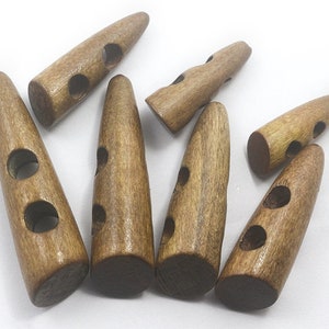 May include: Seven brown wooden toggle buttons with two holes each. The buttons are shaped like a pointed cone.