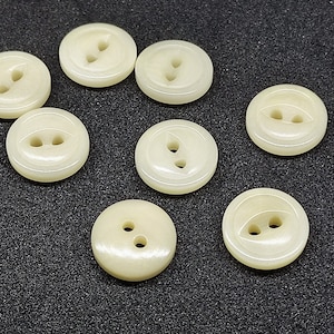 May include: Eight off-white plastic buttons with two or three holes each.