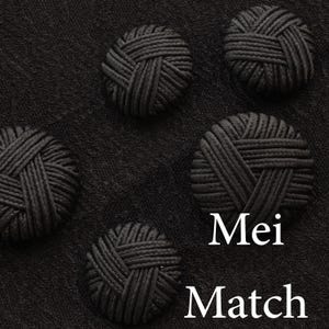 Puede incluir: Cuatro botones redondos negros con un diseño tejido. Los botones están sobre un fondo de tela negra. El texto "Mei Match" está escrito en blanco debajo de los botones.