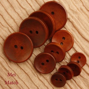 May include: A set of 10 brown wooden buttons, each with two holes. The buttons are arranged in a circle, with the largest button in the centre and the smallest button on the outside.
