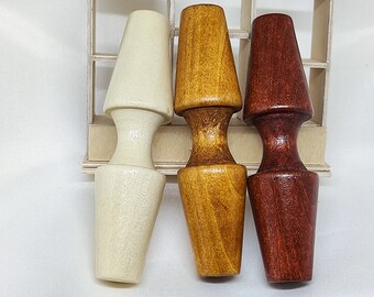 Op de afbeelding: Drie houten flessenstoppers in verschillende kleuren: wit, geel en rood. De stoppers zijn kegelvormig met een afgeronde bovenkant en een cilindrische basis.