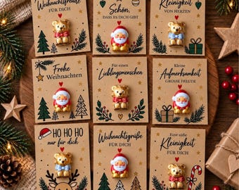 May include: Nine rectangular kraft paper cards featuring Christmas-themed illustrations and German text, each displaying a small, three-dimensional figurine of either a teddy bear or Santa Claus attached to the center of the card.