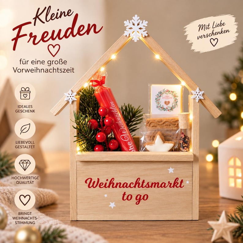 May include: A wooden house-shaped gift box with the text "Weihnachtsmarkt to go" and "Kleine Freuden". It contains a red candle, green pine branches, a small glass bottle with dried spices, and cookies in clear packaging, illuminated by small LED lights.