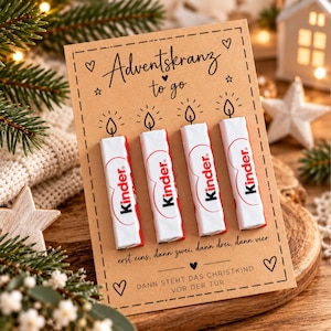 May include: A rectangular brown card featuring the text Adventskranz to go with four Kinder chocolate bars attached vertically. The card includes illustrations of four candle flames above the bars and German text below them, decorated with hearts and stars.
