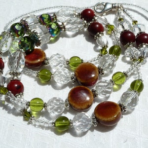 May include: A multi-strand necklace with clear crystal beads, green glass beads, and brown and red ceramic beads.