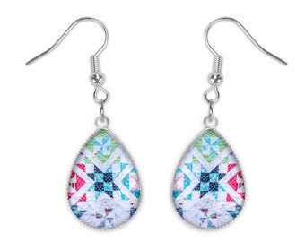 May include: A pair of silver teardrop earrings with a colorful geometric pattern. The earrings feature a white background with blue, green, pink, and red accents.