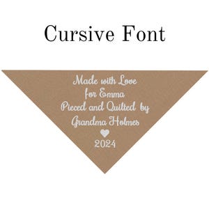 May include: A brown triangle-shaped tag with white text that reads "Made with Love for Emma, Pieced and Quilted by Grandma Holmes" and a white heart with the year "2024" below it.