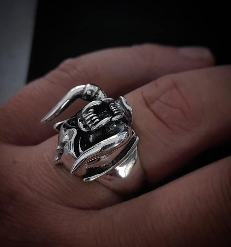 May include: A silver ring with a detailed design of a snarling beast with fangs and horns.