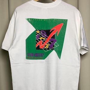 Könnte beinhalten: Weißes T-Shirt mit Grafik auf der Rückseite. Das Design umfasst grüne, weiße und violette Elemente mit einem roten Pfeil. Der Text lautet "ADVANCED MICRO DEVICES" und "AMD 80C287 Math Coprocessor".