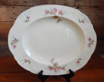 Könnte beinhalten: Eine große, ovale, weiße Keramik-Servierplatte mit Blumenmuster. Die Blumen sind rosa, grün und blau.