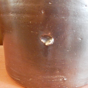 K&ouml;nnte beinhalten: Ein brauner Steinzeugkrug mit einem kleinen Abplatzen an der Seite.