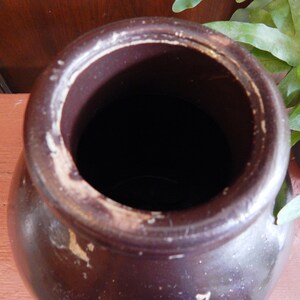 K&ouml;nnte beinhalten: Eine braune Keramik-Vase mit einer breiten &Ouml;ffnung und einem wei&szlig;en Rand. Die Vase ist leer und hat ein rustikales Aussehen.