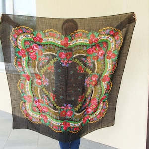 May include: A black square scarf with a floral design. The scarf features a central floral pattern with red roses, green leaves, and accents of yellow and purple. The border has a scalloped edge.