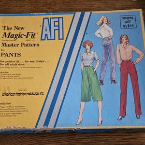 May include: A vintage sewing pattern box for pants, featuring illustrations of women in various pant styles. The box is blue and yellow with the text "The New Magic-Fit Master Pattern for PANTS" and "American Fashion Institute, inc."