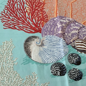 May include: A light blue fabric featuring a marine-themed print with a large red coral branch, a white coral structure, a purple spiral seashell, a white and blue nautilus shell, a brown and white striped shell, and three small black shells.