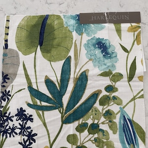 Könnte beinhalten: Ein weißer Stoffmuster mit einem floralen Muster mit blauen, grünen und gelben Blumen und Blättern. Das Stoffmuster hat ein HARLEQUIN-Etikett.