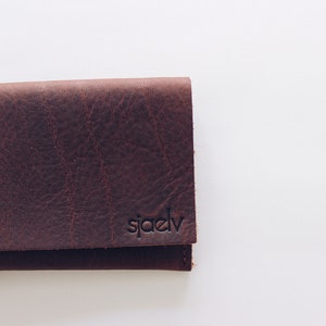 May include: A brown leather wallet with a brass button and the word "sj&aelig;dv" embossed on the front.