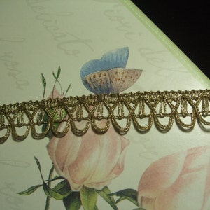 May include: Gold trim with a scalloped edge. The trim is made of a woven fabric with a metallic sheen.
