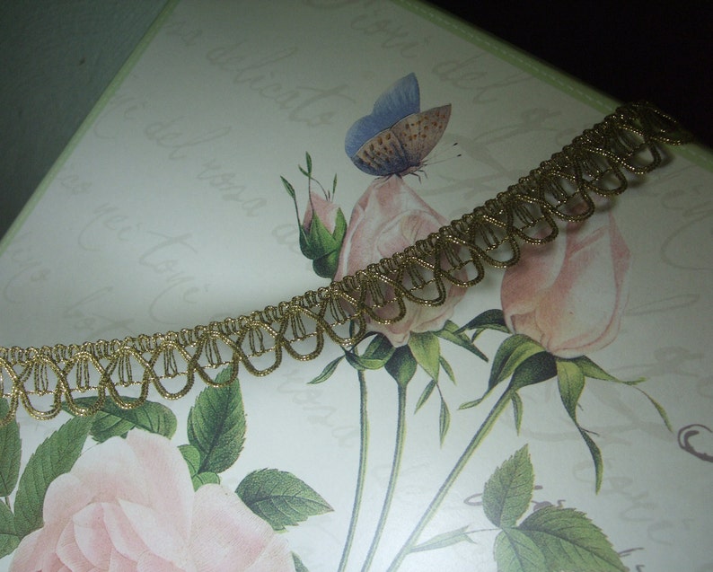 May include: Gold trim with a scalloped edge. The trim is on a white background with a floral design.