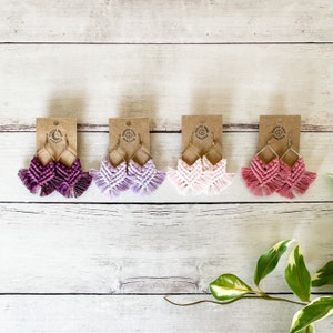 May include: Four pairs of handmade macrame earrings in shades of pink, purple, and red. The earrings are displayed on brown card stock with the text "boho knot company" printed on each card.
