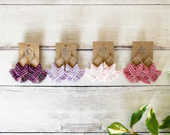 May include: Four pairs of handmade macrame earrings in shades of pink, purple, and red. The earrings are displayed on brown card stock with the text "boho knot company" printed on each card.