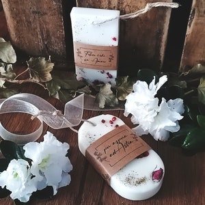 Può includere: Due cere per la fusione bianche con etichette di carta marrone. L'etichetta superiore dice "Felicita echi sa Amore" e l'etichetta inferiore dice "per essere ed Astre". Le cere per la fusione sono decorate con fiori secchi e bacche rosse.